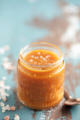 Glass jar with salted caramel and spoon on the table