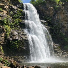Obraz premium Majestic Waterfall Cascading Down Rocky Cliff