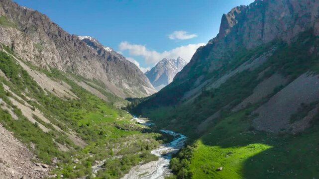 Footage depicts a beautiful creek river flowing through the valley between two large mountains in Ala Archa National Park, Kyrgyzstan.