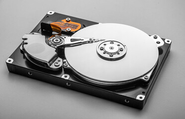 Open hard disk drive reveals its shiny platter, actuator arm, and internal mechanical components in...