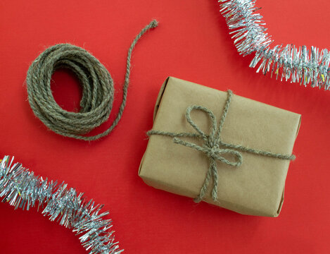 New Year's postcard. Gift, twine, tinsel on a red background.
