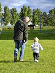 Obraz premium Grandfather and his little grandson run together, play. Children's Day, Family Day.