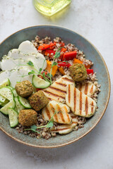 Rustic plate with halloumi cheese, quinoa, falafel and vegetables, vertical shot, middle closeup