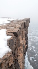Snow Covered Cliff Edge Overlooking a Vast Plain Under a Pale Sky