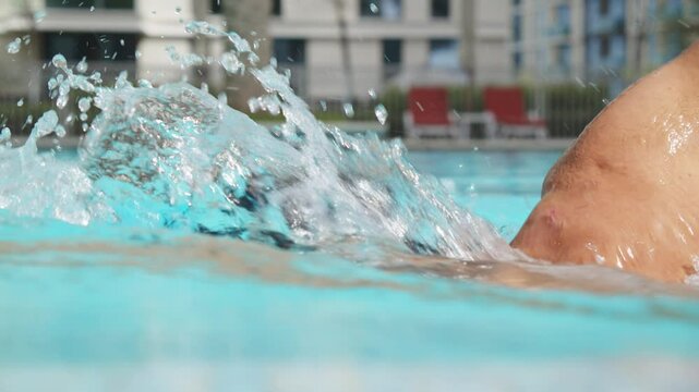 Closeup shot of Professional swimmer swims in an outdoor pool in freestyle style - slow more video. Young pro swimmer athlete conducts a training session. Healthy lifestyle  concept.