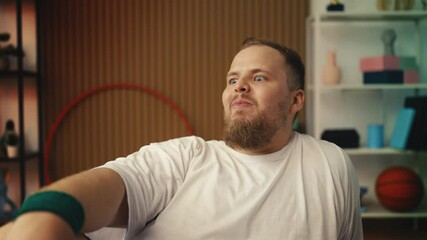 Plus-size man eating apple after home workout, weight loss motivation, dieting