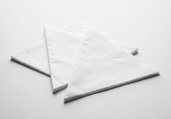 Two white paper napkins stacked on a white surface in a simple, minimalist composition