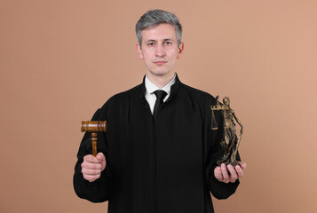 Judge with mallet and statue of Lady Justice on beige background