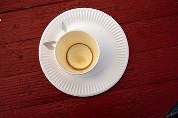 Top view of a used paper coffee cup with visible dried stains and leftovers on a disposable white...
