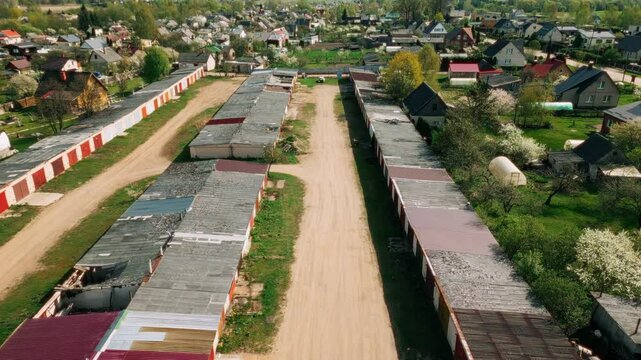 Wide aerial view of long garage rows with corrugated rooftops and sandy paths in a green suburban neighborhood. Location: Daugavpils, Latvia (Daugavpils, Latvija)