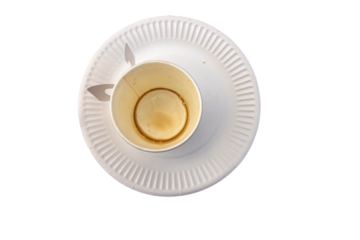 Top view of an iolated used white paper coffee cup with visible coffee stain rings placed on a disposable white paper plate
