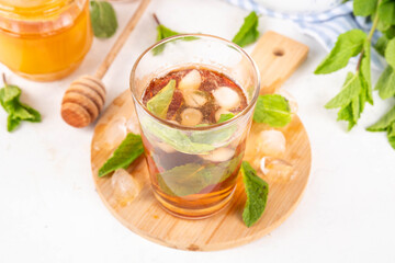Mint and honey iced tea drink, cold summer refreshment cold beverage with a lot of mint leaves, honey and iced cubes, copy space