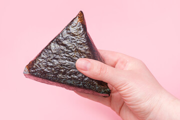 Female hand holding korean samgak close-up on pink background. © TATIANA KIM