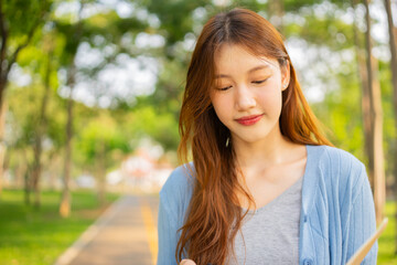 Fototapeta premium Asian woman seeks knowledge and learning in nature park