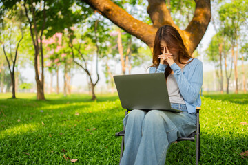 Businesswoman working on laptop stressed in park freelance nature
