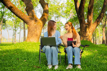 Fototapeta premium Two Asian businesswomen working together in a nature park.