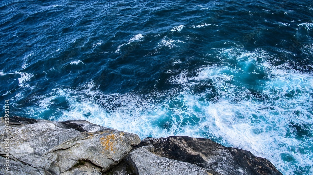 Poster ocean waves crashing against grey rocks, a high-angle view showing the powerful turquoise water and 