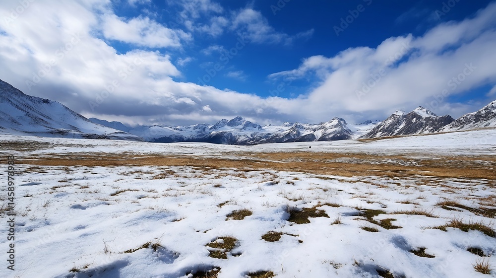 Poster snowy mountain valley landscape with patches of brown grass under a partly cloudy blue sky. a solita