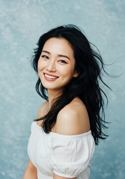 Portrait of a smiling woman with shoulderless top against blue wall