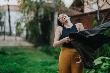 A happy woman laughing while interacting in an outdoor garden setting. She exudes cheerfulness and...