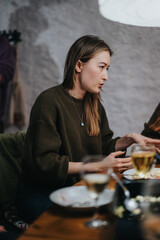 A woman in a casual sweater engages in conversation at a warmly lit restaurant table, creating a friendly and welcoming ambiance.