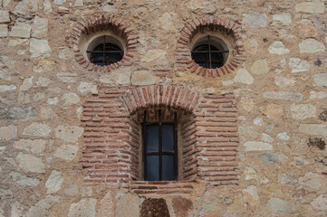Pareidolia. Two circular windows and an elongated window, which looks like a face in a stone wall in the town of Pedraza, province of Segovia. Spain