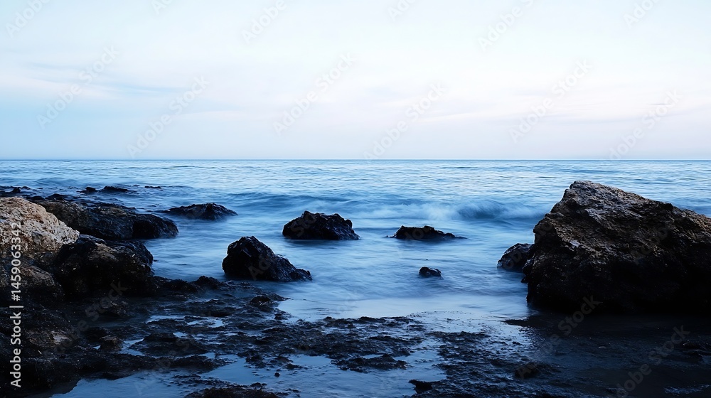 Poster Serene coastal scene at twilight, featuring dark rocks partially submerged in calm, blue water under a pale sky.  The long exposure captures the gentle movement of the waves. : Generative AI