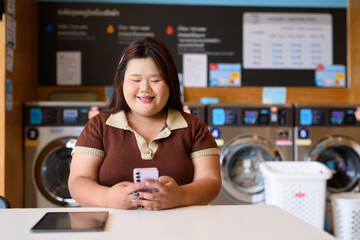 young woman using phone in laundry shop