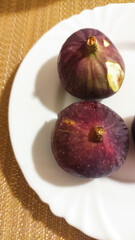 Fresh ripe figs arranged on a white plate showcasing rich purple skin and unique textures inviting culinary creativity and healthy snacking options for food enthusiasts