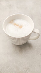 Creamy frothy coffee in elegant white cup resting on smooth surface with inviting warmth and comfort appeal