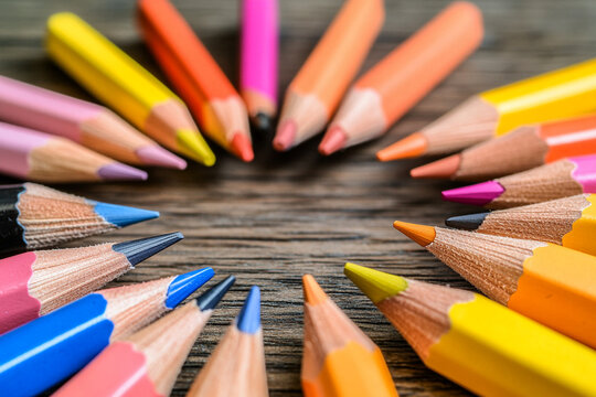 Close-up view of vibrant colored pencils arranged in a circular pattern on a wooden surface
