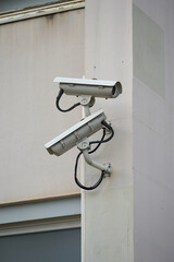 Two outdoor surveillance cameras on the wall, security system. Surveillance cameras are installed at the industrial site to secure the area.