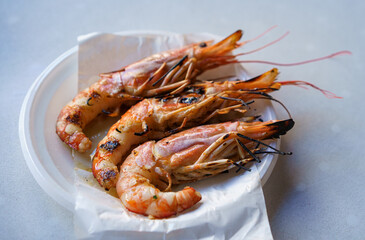 Grilled shrimp served on a white plate on the table.