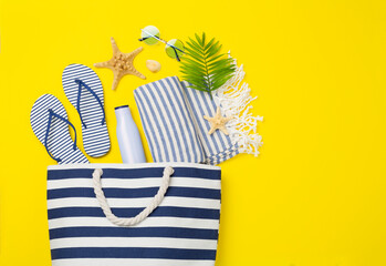 Blue beach bag with summer accessories on color background, top view
