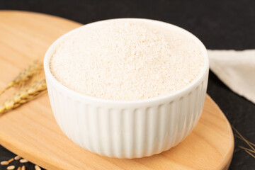 Bowl with spelt flour on wooden table