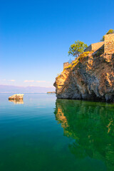 Naklejka premium Lake Ohrid, North Macedonia, April 13 2024. Mountain range and peninsula in distance. Ohrid Lake, Macedonia, Europe. The clear mesmerizing waters of lake Ohrid with a beautiful view. 
