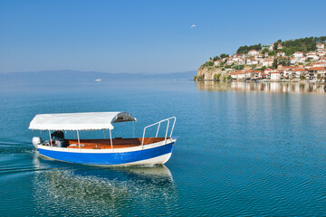 Obraz premium Lake Ohrid, North Macedonia, April 13 2024. Mountain range and peninsula in distance. Ohrid Lake, Macedonia, Europe. The clear mesmerizing waters of lake Ohrid with a beautiful view. 