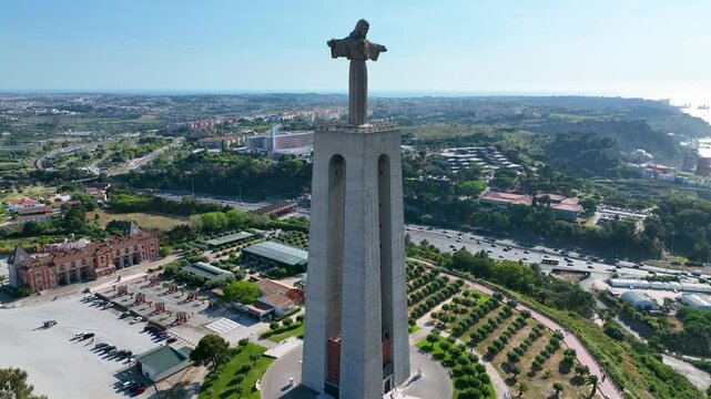 Almada, Portugal - May 12, 2024: Aerial view of the Cristo Rei monument with urban landscape of Almada in the background, showing parks, roads, and residential areas