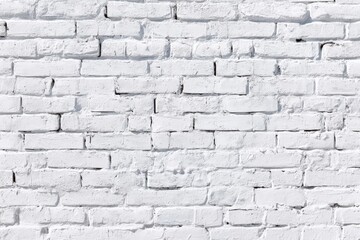 Fototapeta premium A white-painted brick wall with a rough, textured surface and visible mortar lines.