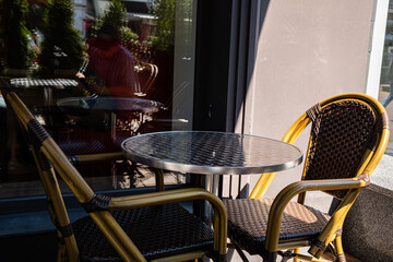 Sunlight casts gentle shadows on the wicker chairs and gleaming table, enhancing the cafe's charm