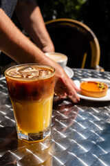 Sunlight shines through trees as a cool drink and dessert are enjoyed in a cozy café