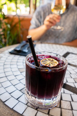 Brightly colored drink with a lemon slice awaits enjoyment while friends relax at a cafe