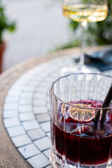 A chilled beverage with lemon accents sits on a mosaic table as sunlight filters through greenery
