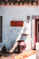 Rustic mock-up of a blank ceramic nameplate on a traditional Mediterranean house wall, ideal for adding custom text or logo; surrounded by vintage decor and sunlit textures for authentic charm