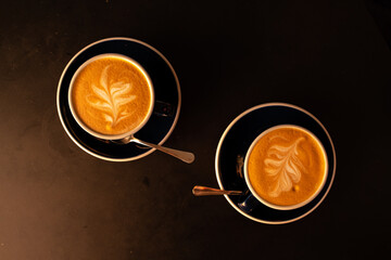 Two elegant lattes with artful foam designs rest on dark tables, inviting warmth and comfort