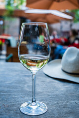 A glass of chilled white wine rests on a rustic table, capturing the essence of a lively gathering