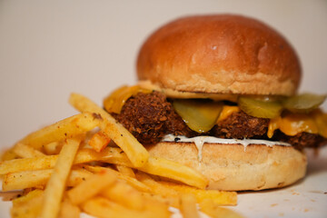Close up view of french fries and hamburger with meat, pickled gherkins slices, and cheese isolated on white background.