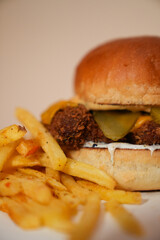 Close up view of french fries and hamburger with meat, pickled gherkins slices, and cheese isolated on white background.
