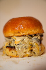 Close up view of hamburger with meat, mushroom, sauce, and melted cheese isolated on white background.
