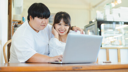 Asian couple from lgbtq community enjoy lifestyle activity together using laptop in cozy indoor setting with warm expressions